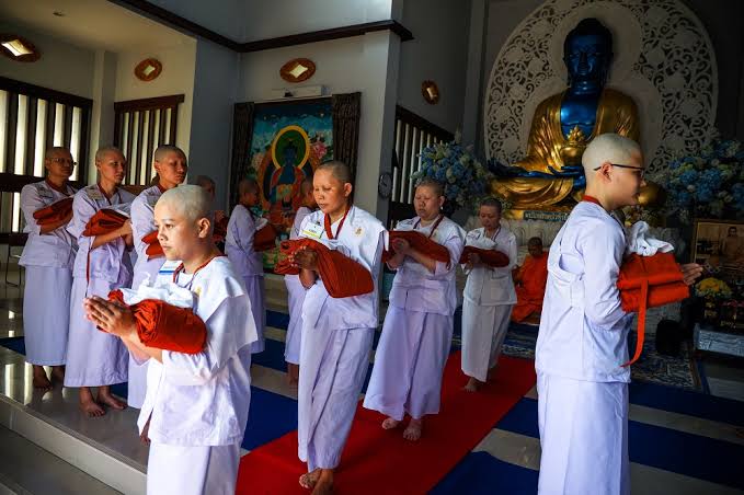 Young Thai school children in uniforms performing the traditional Wai gesture bowing with hands pressed together to show respect