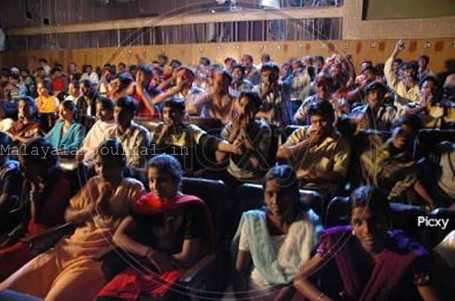 A crowded cinema theater with young audiences cheering