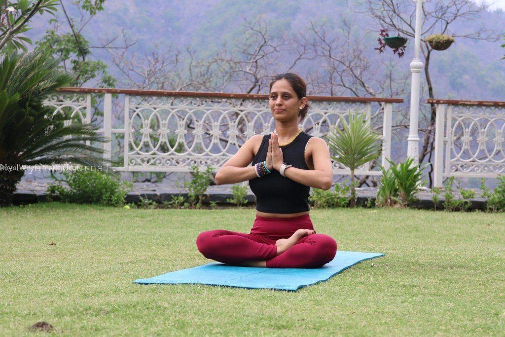 Woman meditating on a yoga mat outdoors.