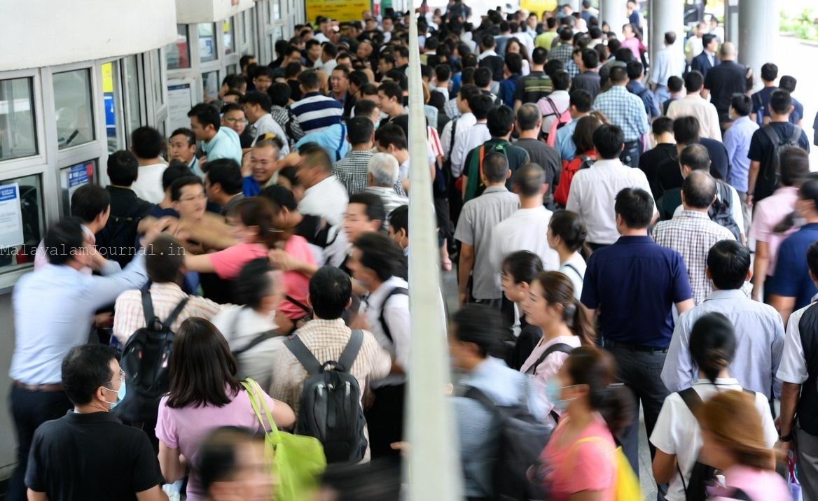 People standing in a crowded unorganized queue in public place.