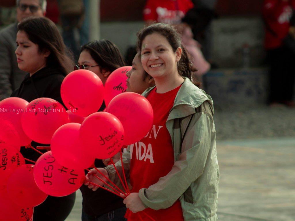 A woman holding a bunch of red balloons